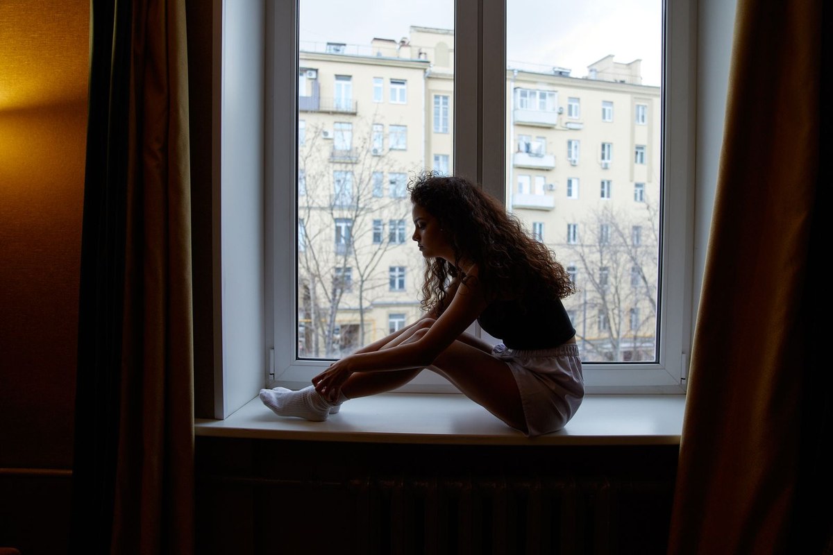 Personne assise près d'une fenêtre au cours d'un moment de réflexion