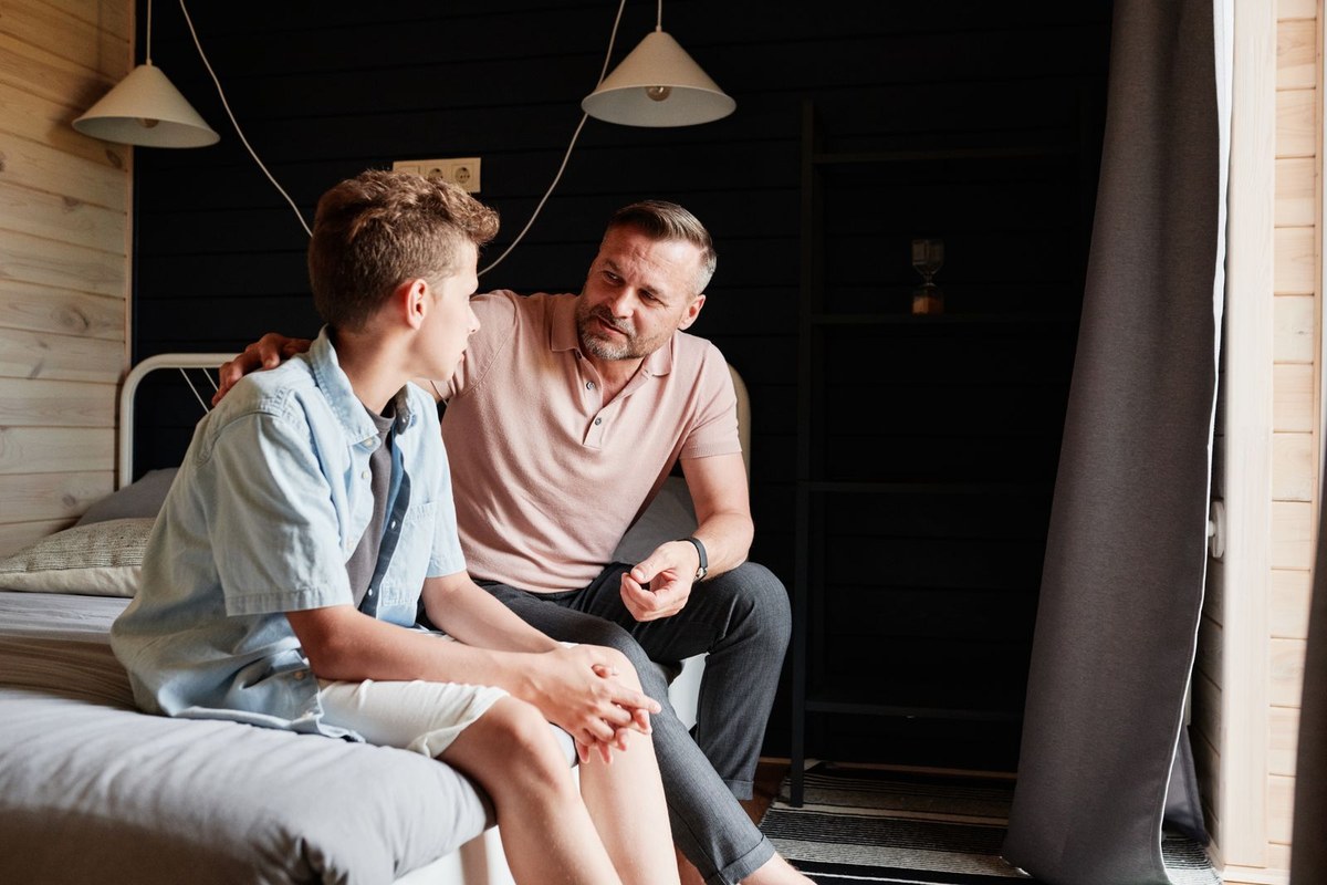 Père échangeant calmement avec son adolescent à la maison