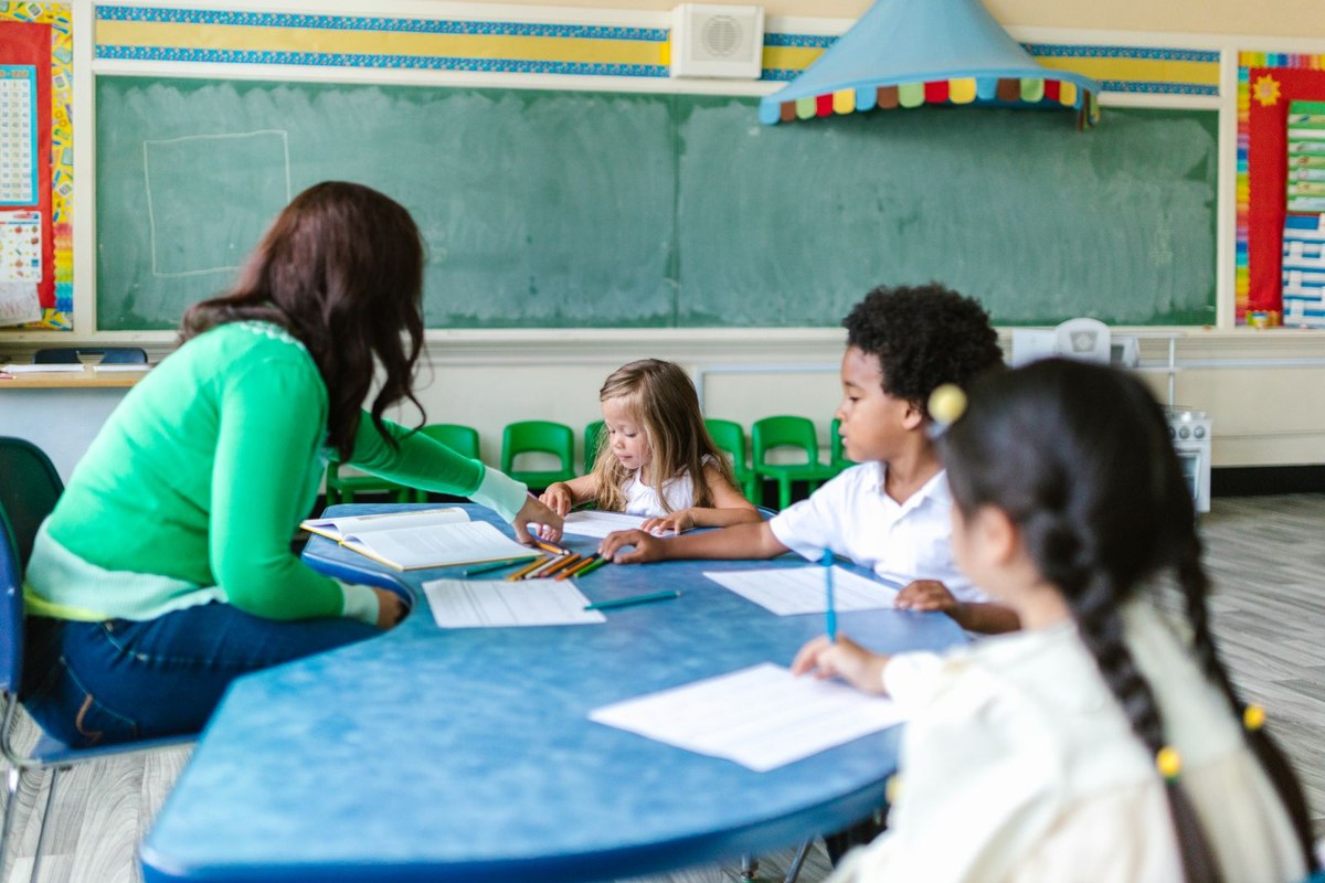 Enfants accompagnés par une enseignante dans une salle de classe
