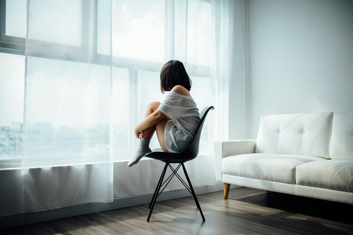 Personne assise près d’une fenêtre dans un moment de réflexion