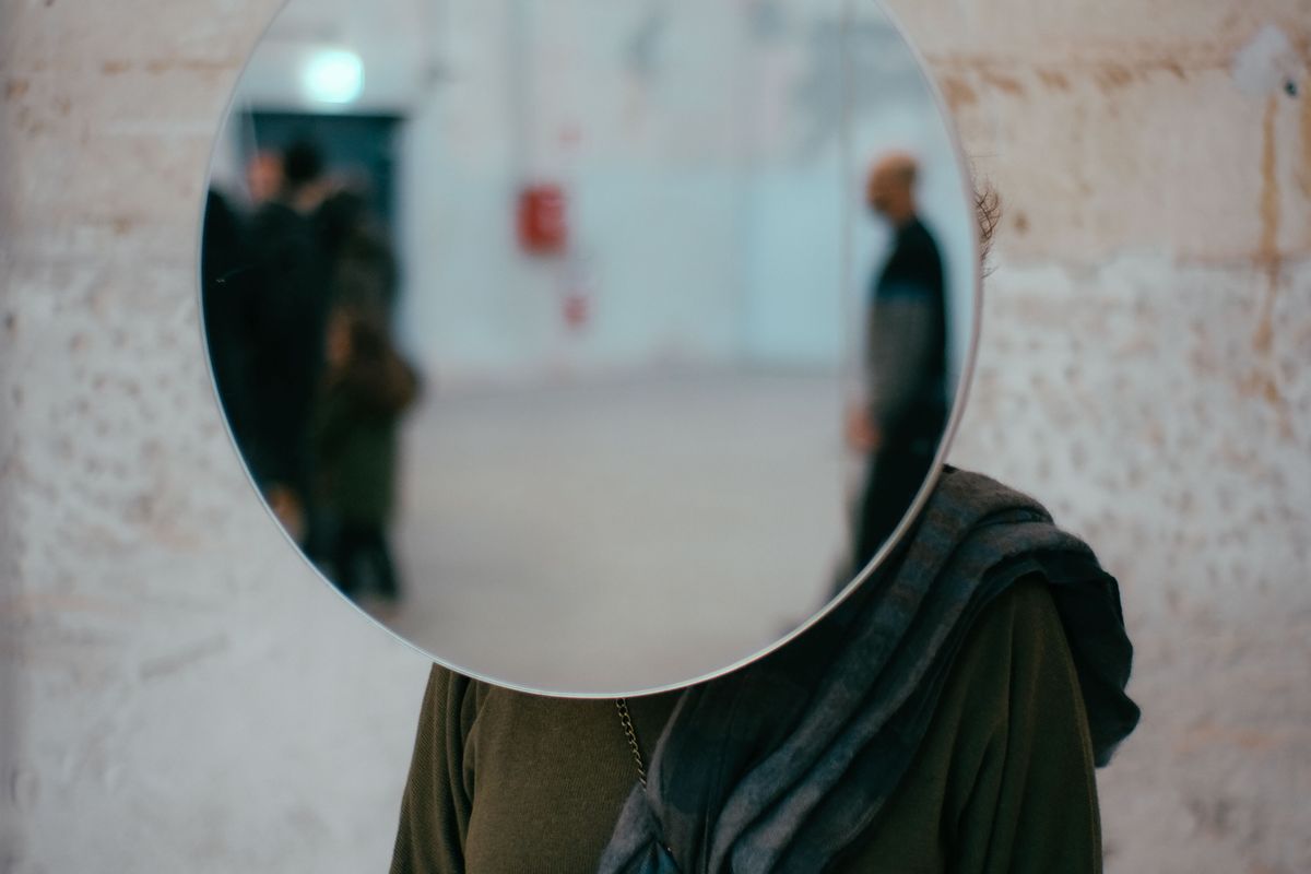 Personne tenant un miroir devant son visage